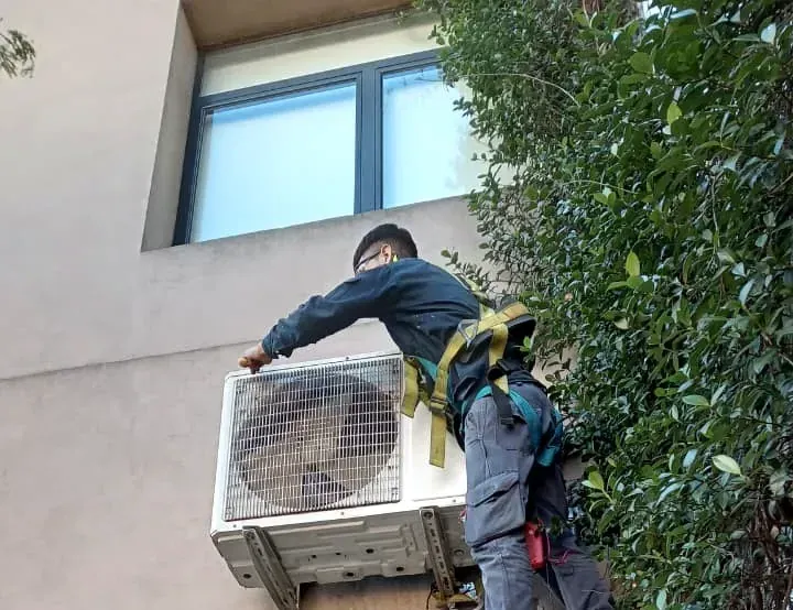 Técnico de Econex con arnés instalando una unidad exterior de aire acondicionado